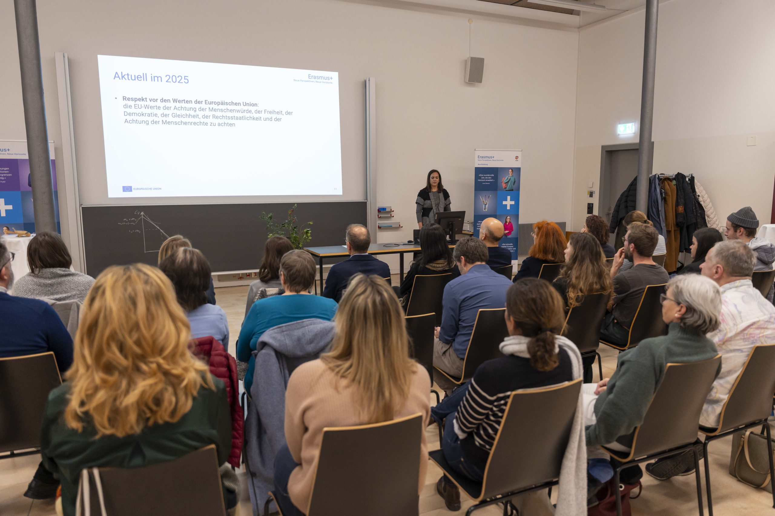 Besunchende des Info-Anlasses zum Call 2025 hören den Neuigkeiten zu und schauen auf die Präsentation