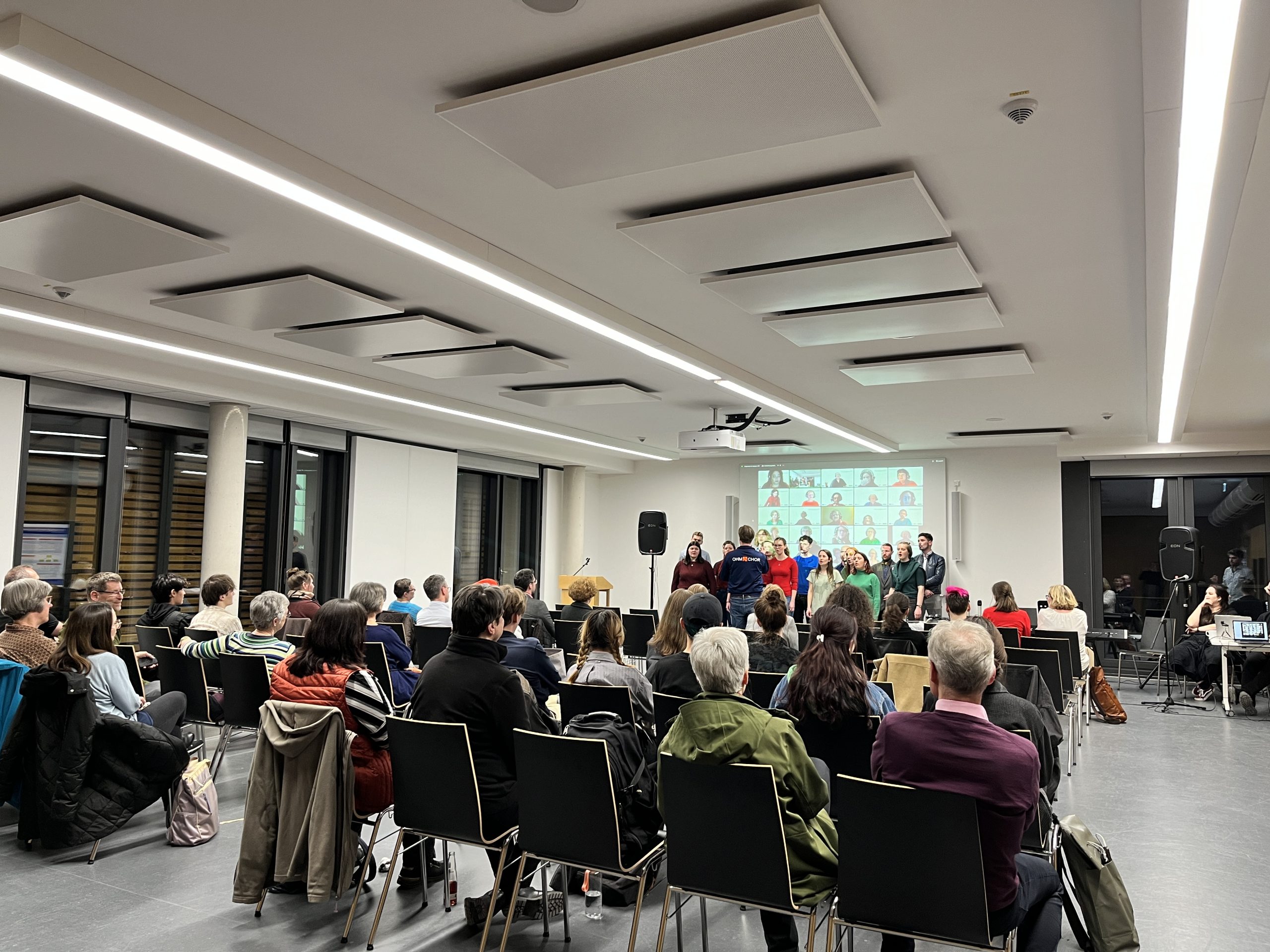 Chor singt vor Publikum mit Online-Teilnehmenden