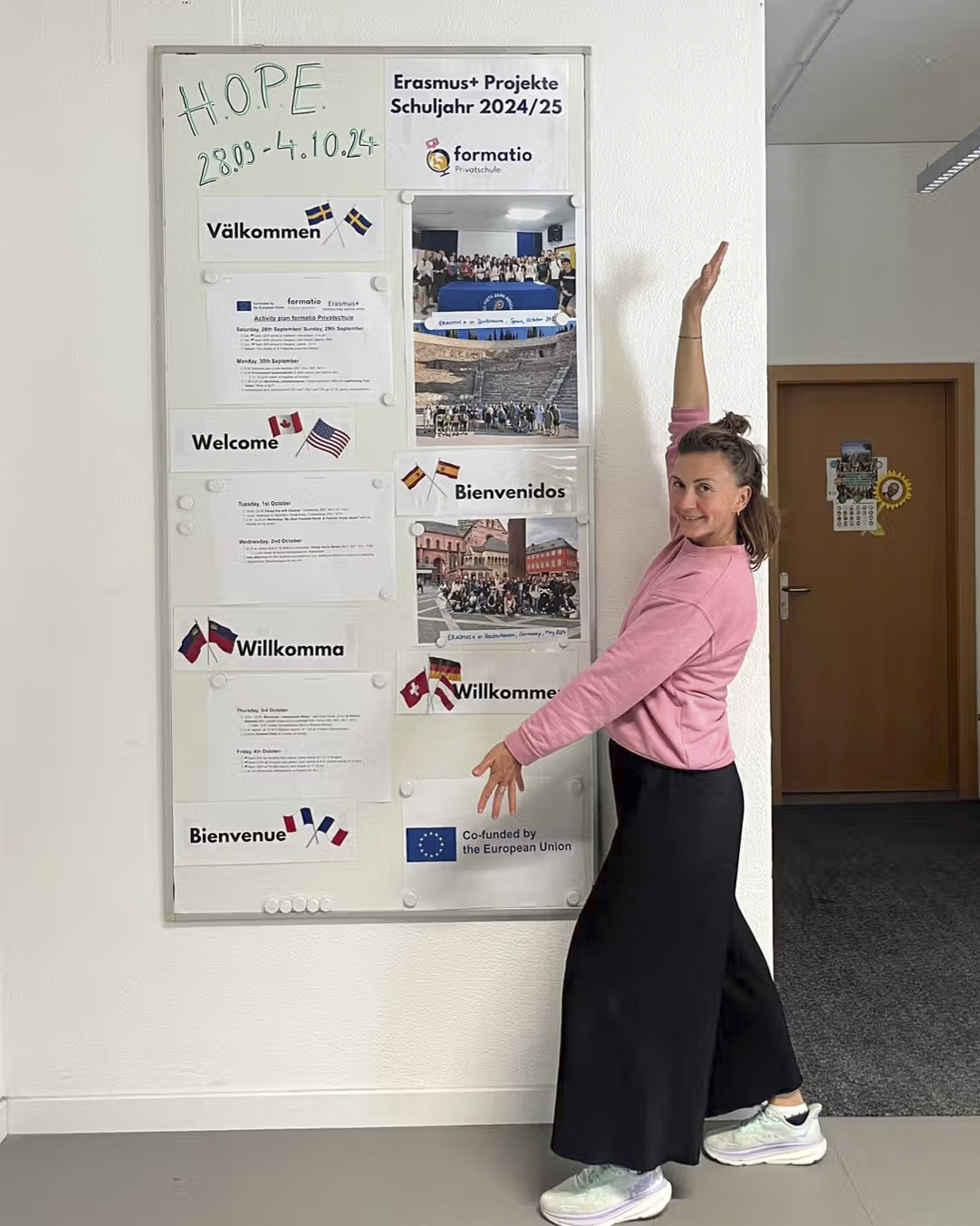 Person steht neben einer Infotafel zum Erasmus+-Projekt mit Begrüssungen in mehreren Sprachen