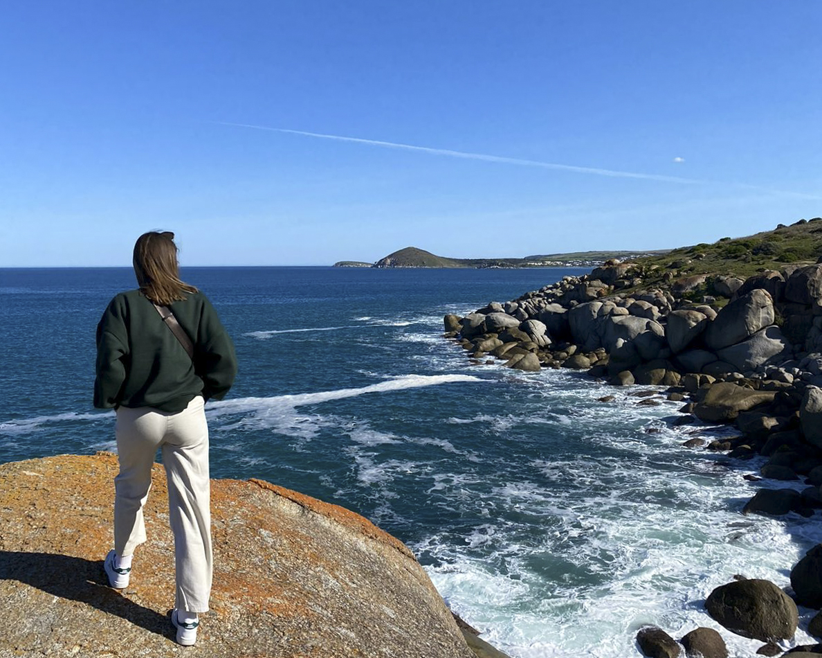 Frau steht auf Fels und schaut auf das Meer in Australien