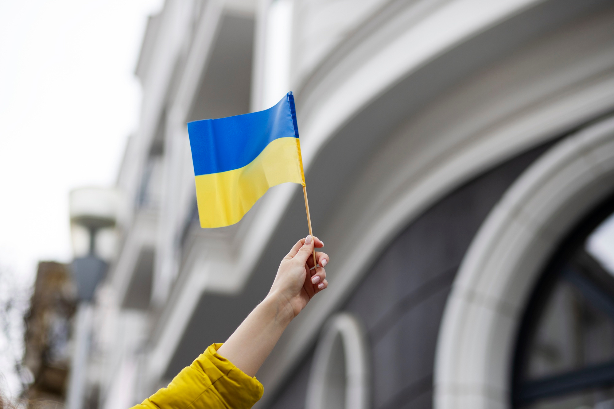 Person hält eine kleine Ukrainische Flagge mit der Hand in die Höhe