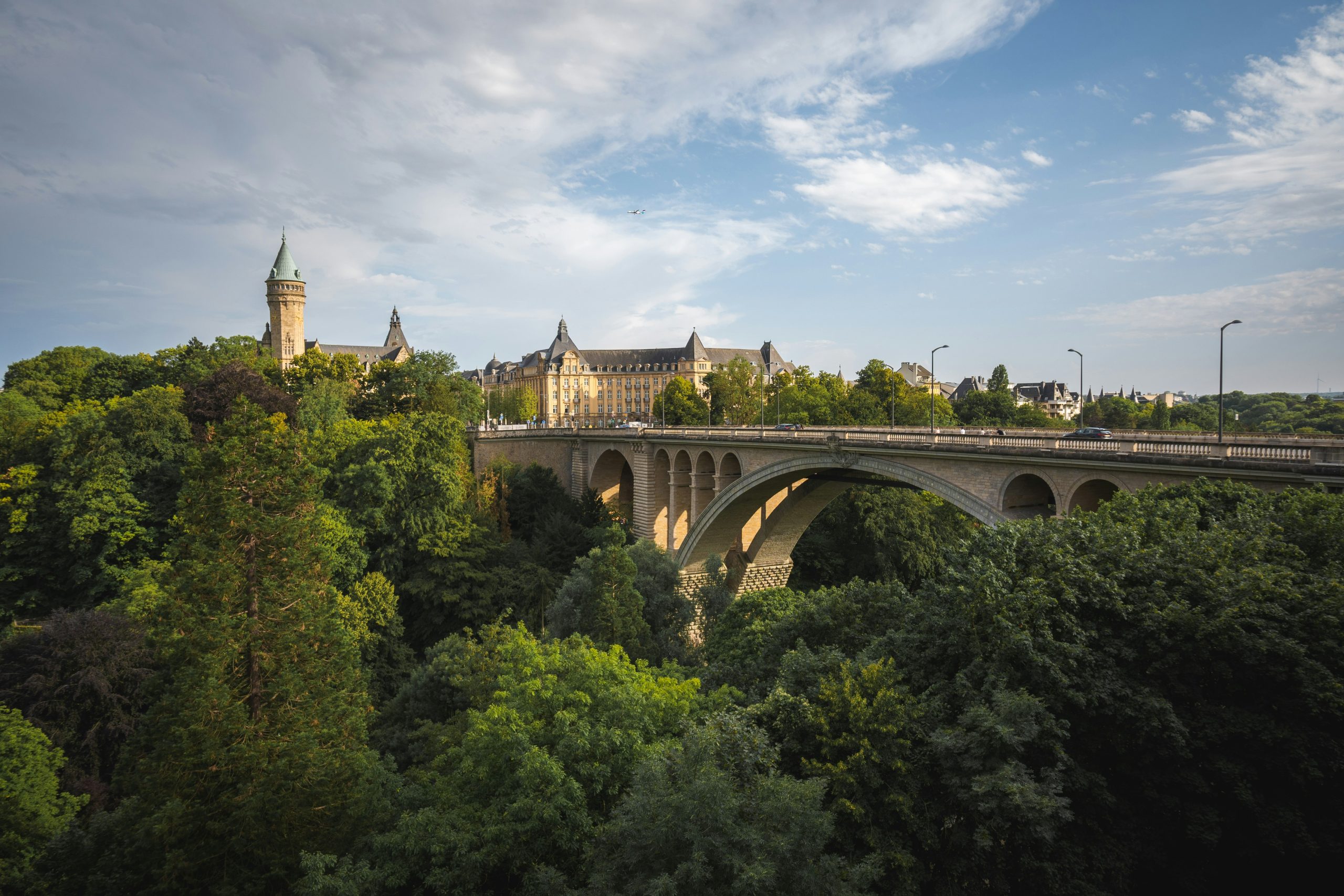 Br&uuml;cke f&uuml;hrt &uuml;ber einen Wald, dahinter schaut ein Turm aus den B&auml;umen in Luxemburg